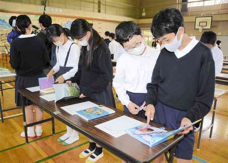 気になる本のページをめくりながら投票する児童たち＝熊本市中央区