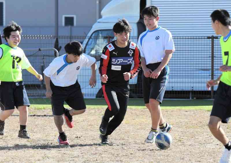 交流会でボールを追いかけるロアッソ熊本のFW坂本亘基（中央）と熊本はばたき高等支援学校の生徒＝熊本聾学校