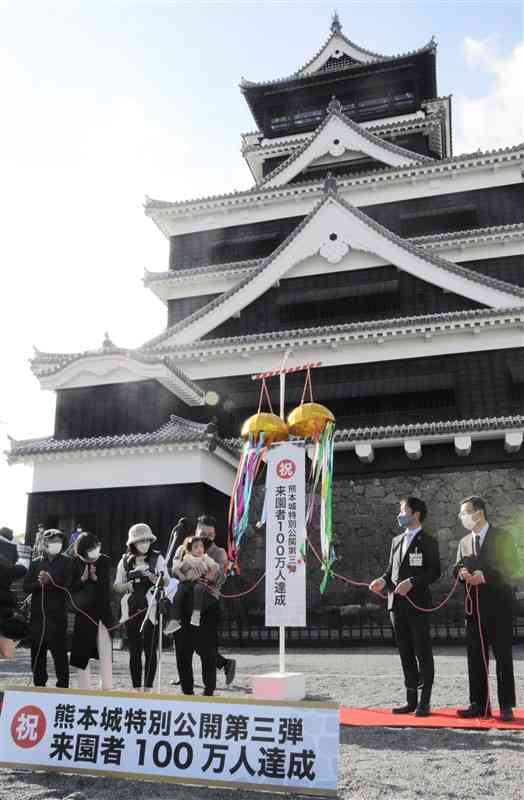 100万人目の入園者となり、熊本城の天守閣前広場でくす玉を割る男性一家（左）と熊本市幹部ら＝26日、熊本市
