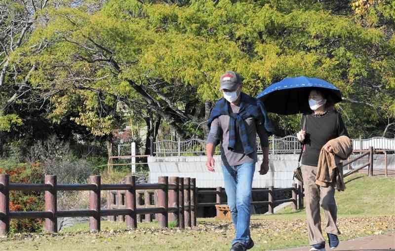 上着を脱ぎ、散歩する人たち＝28日午後2時50分ごろ、熊本市中央区の水前寺江津湖公園（谷川剛）