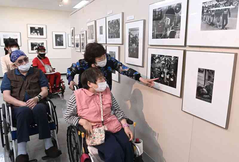 「9人の写真家が見た水俣」展に見入る胎児性や小児性の水俣病患者ら＝5月、熊本市中央区の新聞博物館（小野宏明）