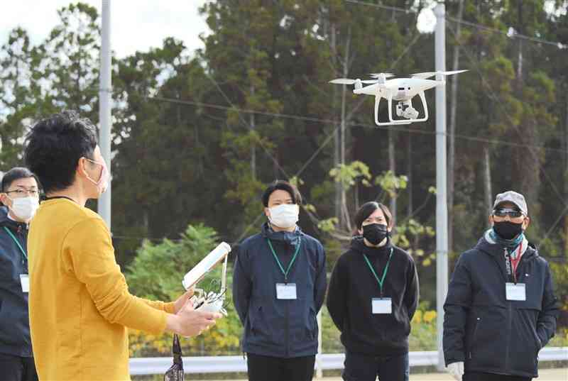 ドローンを使ったカワウ対策の研修会で、「水産研究・教育機構」の研究員（左手前）から操縦技術を学ぶ参加者たち＝山鹿市