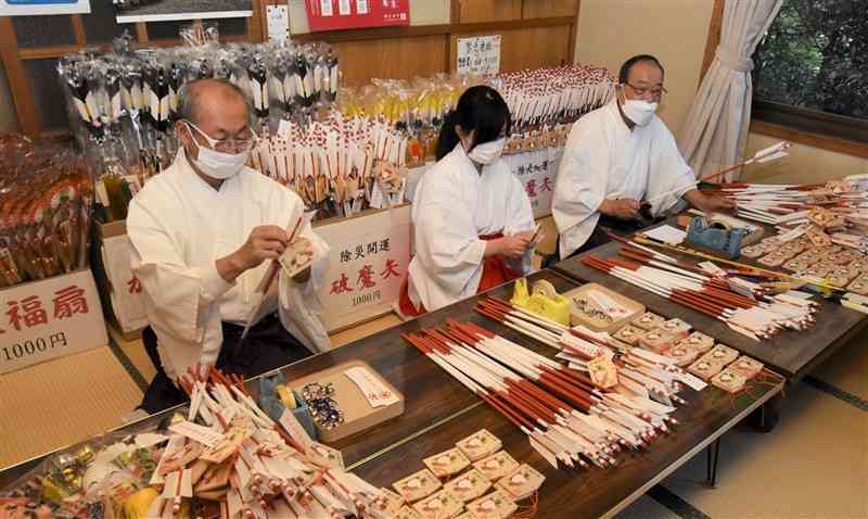 紅白の矢に札や絵馬を取り付ける四山神社の職員＝荒尾市