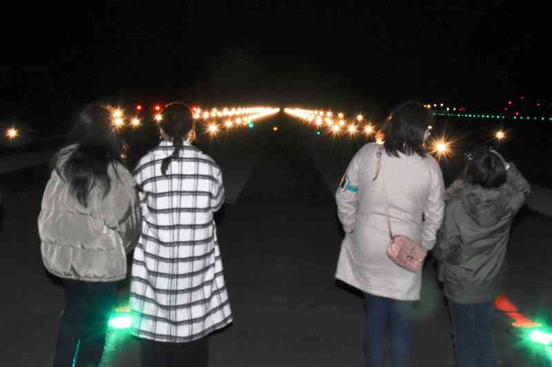 熊本空港の滑走路上で「灯火ライトアップ」を見学する小学生ら＝益城町