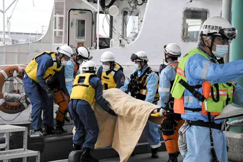 火災が発生した旅客船に見立てた巡視船から負傷者を運び出す海上保安官と救急隊員＝12日、熊本港
