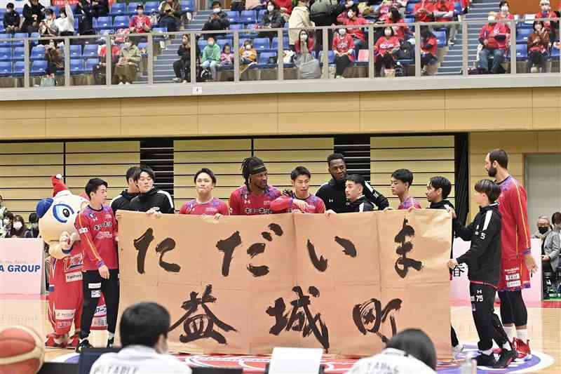試合前、「ただいま益城町」と書いた横断幕を掲げる熊本の選手たち