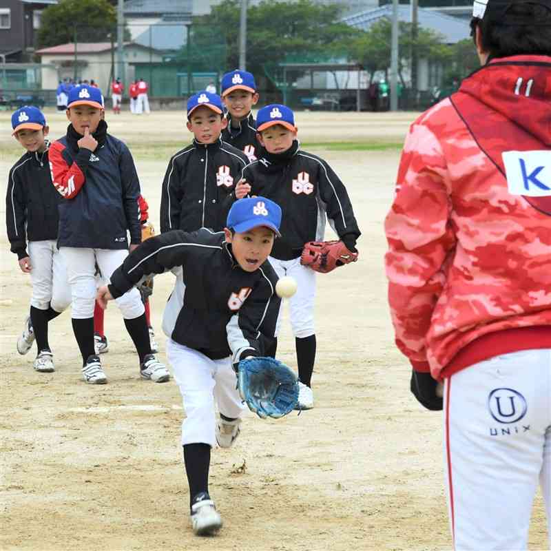 サラマンダーズの選手（右）から捕球の指導を受ける小学生たち＝天草市
