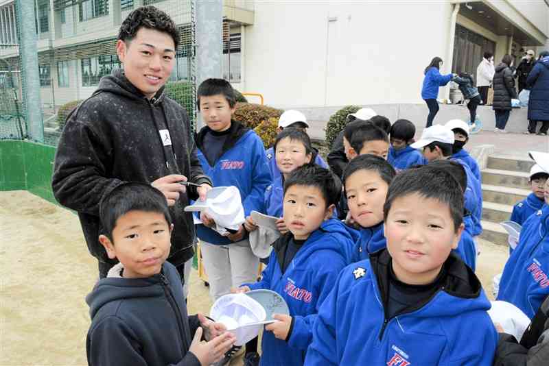 母校の菊陽西小を訪れ、サインに応じるプロ野球西武の中熊大智選手（左）＝菊陽町