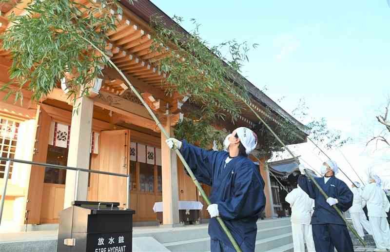 先端に葉を残した竹で拝殿の汚れを落とす神職ら＝阿蘇市