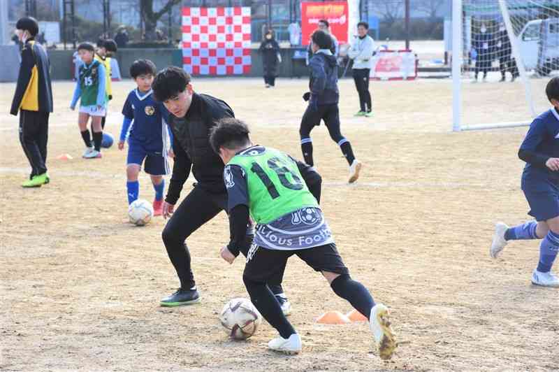 子どもたちにドリブルを教える坂本亘基選手（中央）＝玉東町