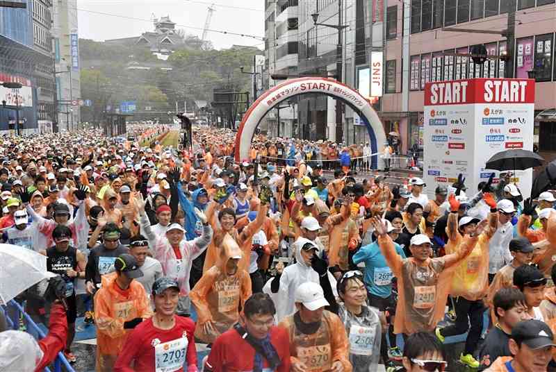 雨の中、熊本城をバックにスタートする第9回熊本城マラソンのランナー＝2020年2月、熊本市中央区の通町筋電停前