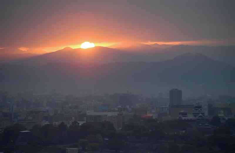 山の稜線と雲の間から姿を見せた2023年の初日の出と熊本市街地。右手前は熊本城＝1日午前7時30分ごろ、同市西区花園の本妙寺公園から撮影（小山真史）