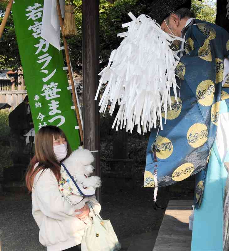 若宮神社の「ガランザサ祭り」で、愛犬の健康を祈願する参拝客の女性（左）＝山鹿市