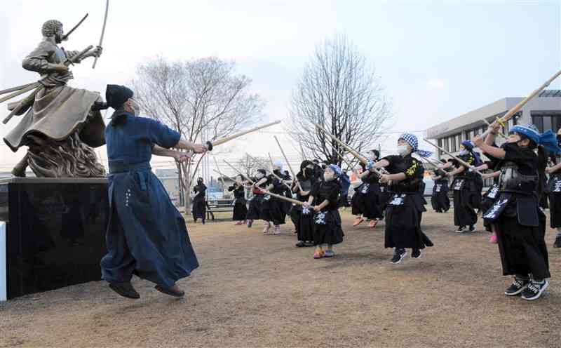 ゾロ像の前で素振りをする小学生剣士たち＝大津町