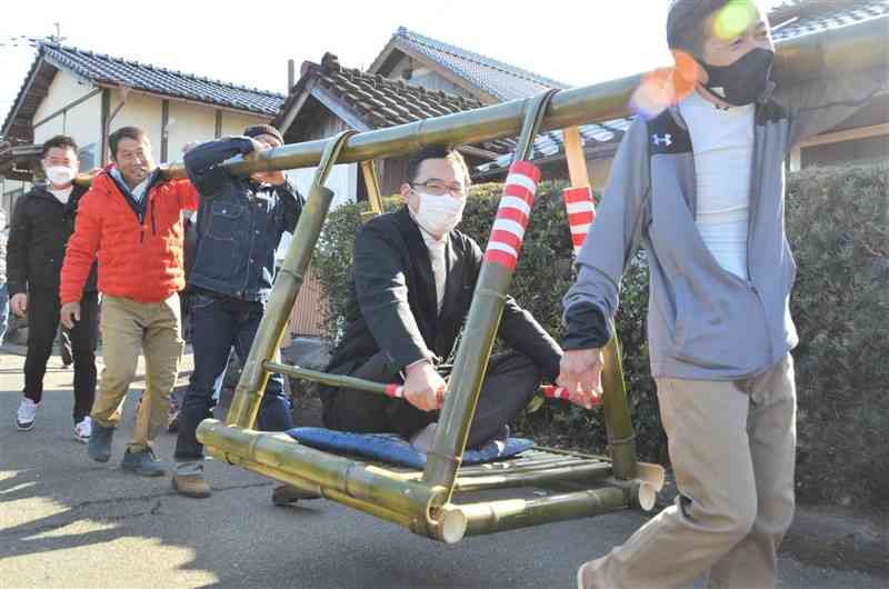 今年厄入りした井伊一さんを竹籠で担ぐ福原地区の住民ら＝益城町