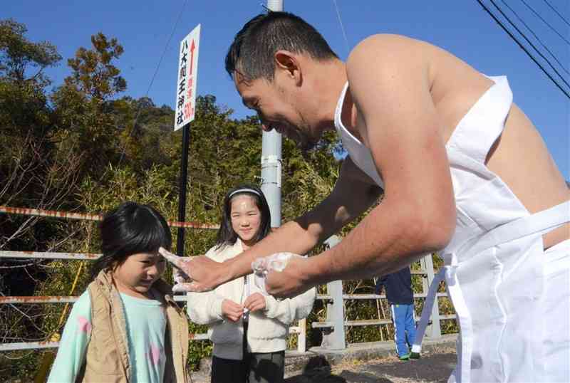 婿役の髙村克士さんから手についたシトギを額につけてもらう子どもたち＝菊池市