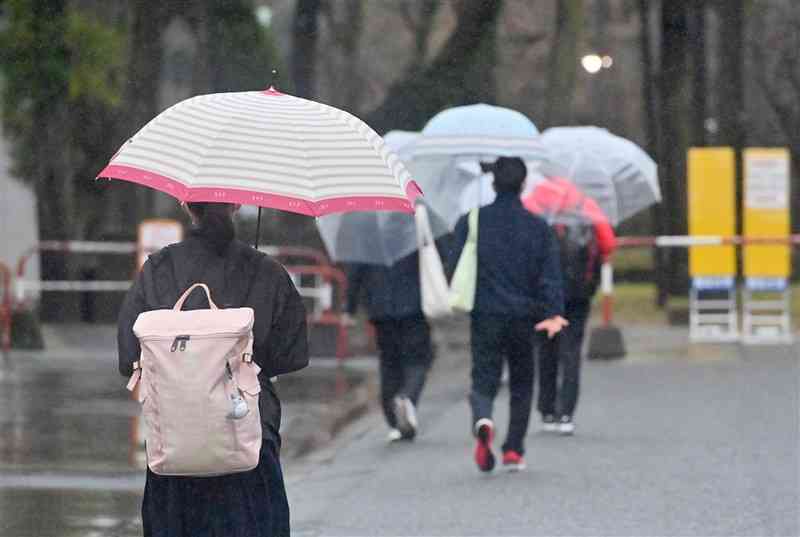 暖かい朝となった大学入学共通テスト初日、小雨の中を傘を差して試験会場へ向かう受験生たち＝14日午前7時50分すぎ、熊本市中央区の熊本大（谷川剛）