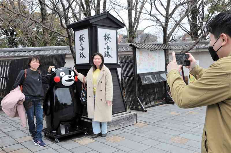 桜の馬場城彩苑でくまモンのオブジェと写真を撮る台湾からの観光客＝14日、熊本市中央区