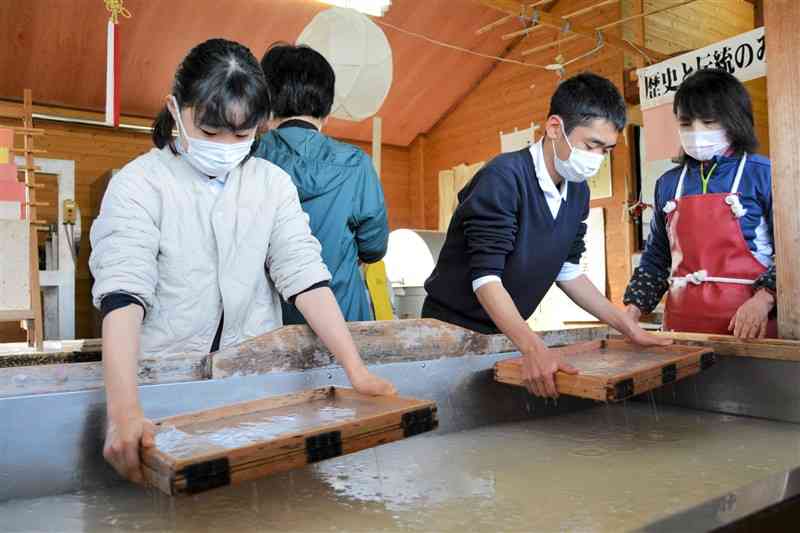 卒業証書になる和紙をすく三加和小の6年生＝和水町