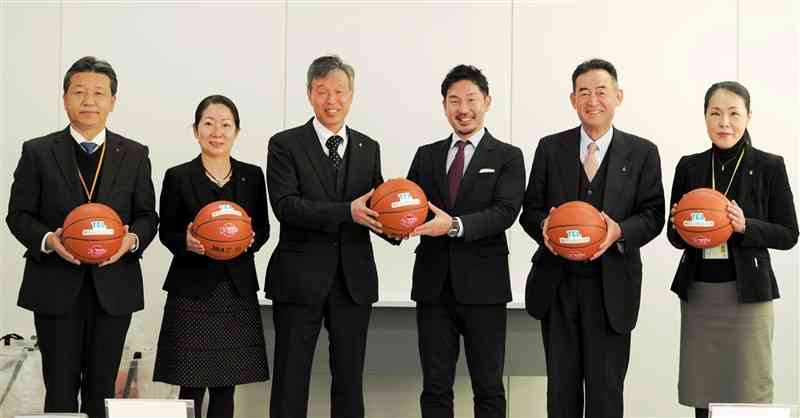 熊本バスケットボールの福田拓哉社長（右から3人目）からボールを受け取る菊陽町内の小学校長ら＝同町