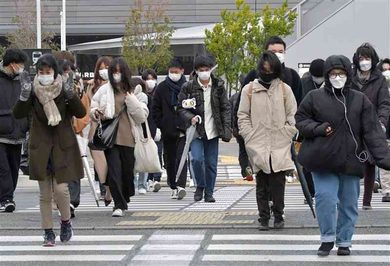 防寒着に身を包み通勤や通学する人たち。奧はJR熊本駅＝24日午前8時10分ごろ、熊本市西区（谷川剛）