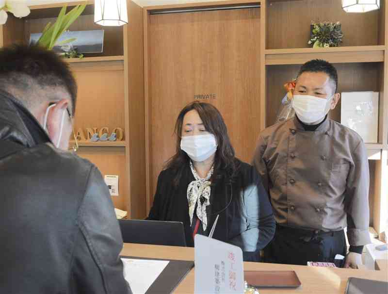 最初の宿泊客を出迎える社長の田中正一さん（右）と妻の由美子さん＝28日、芦北町