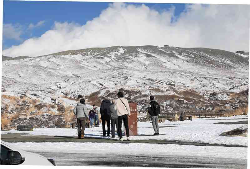 火口から1キロ圏外の展望公園から中岳の噴煙を見上げる観光客ら＝30日午後2時40分ごろ、阿蘇市