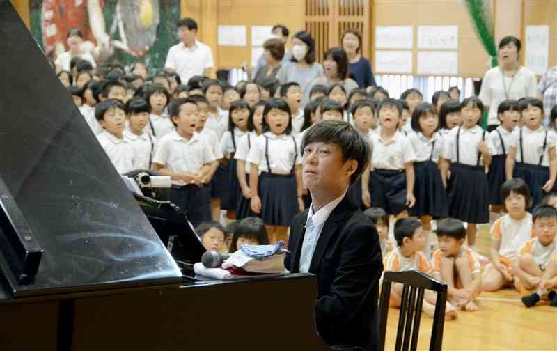 隈府小でピアノの演奏を披露する松本俊明さん（手前）＝2016年9月、菊池市