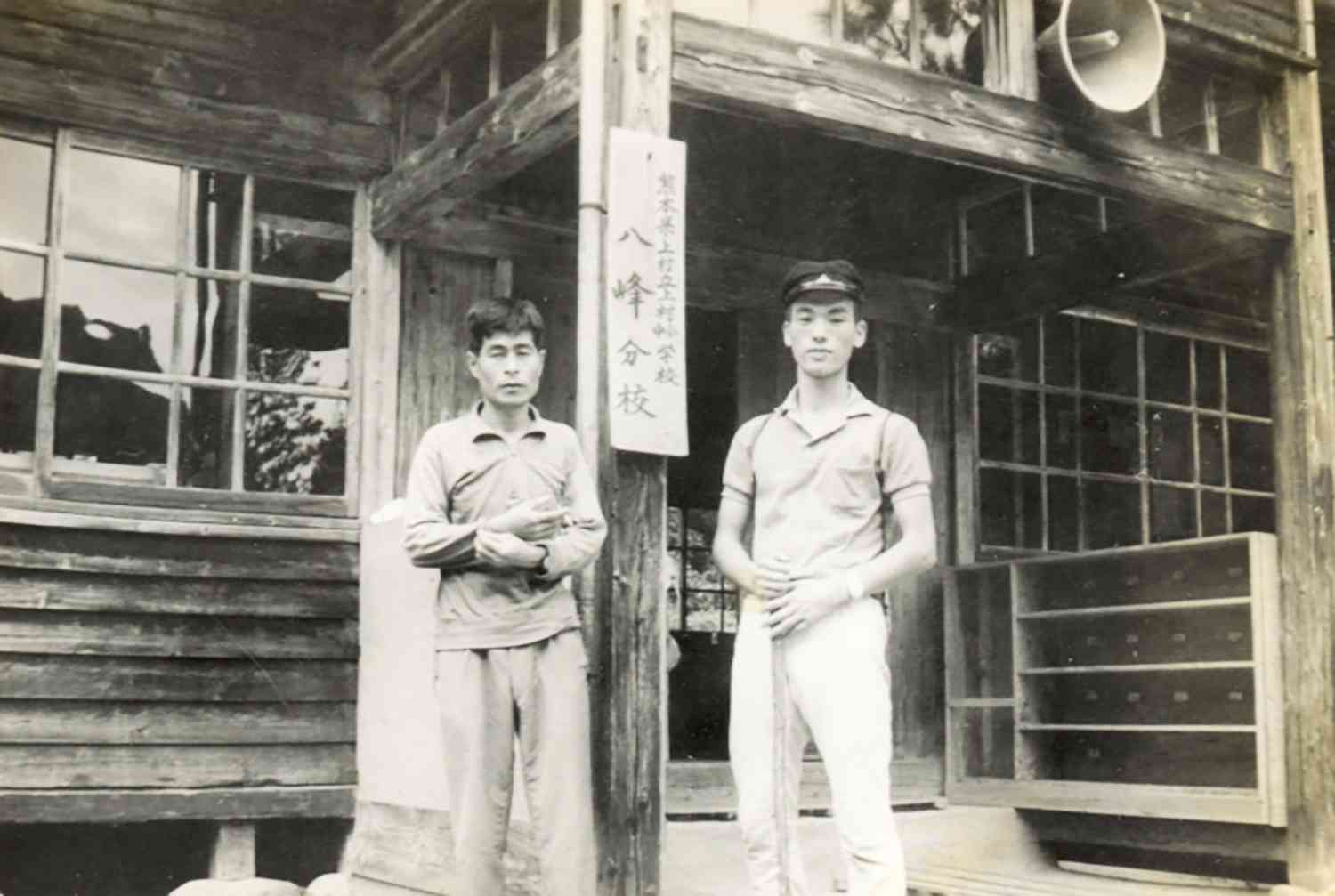 上村立小中学校八ケ峰分校の前に立つ筆者（右）