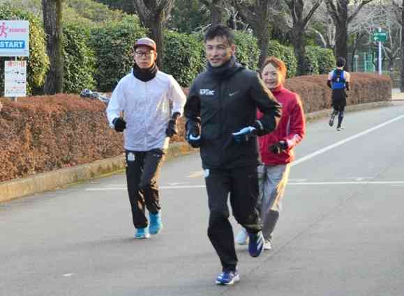 「熊本城マラソン２０２３」の出場を前に、県民総合運動公園を走り込む田尻貴之さん（中央）ら。公園内には早朝から多くのランナーの姿が見られる＝熊本市東区