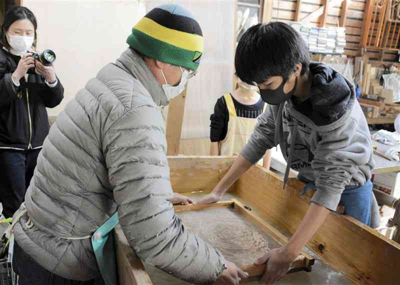 金刺潤平さん（左）から指導を受け、紙すきに挑戦する袋小の児童ら＝水俣市