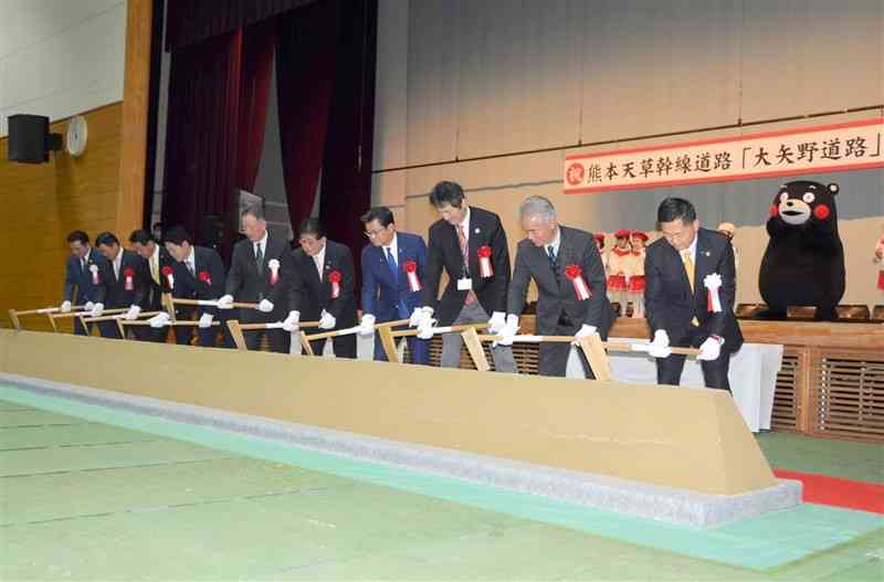 熊本天草幹線道路の一部となる「大矢野道路」の着工式で、くわ入れを行う関係者＝上天草市