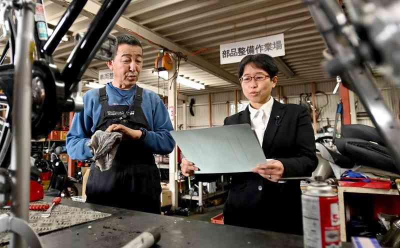 臨時村議会の終了後、夫婦で営むバイクショップで可決議案について意見を交わす西原村議の尾崎幸穂さん（右）と夫の朱実さん＝8日、同村（石本智）