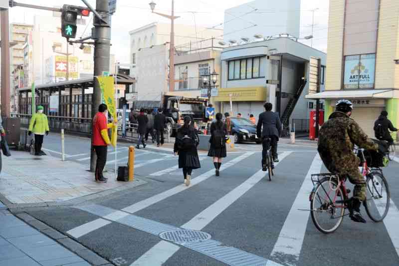 熊本市電の健軍町電停前の交差点でつじ立ちする市議選の立候補予定者ら＝21日、熊本市東区