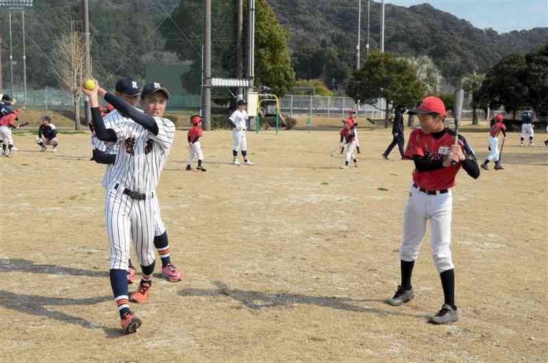 小学生（右）にバッティングのこつを指導する熊本西高野球部員＝上天草市