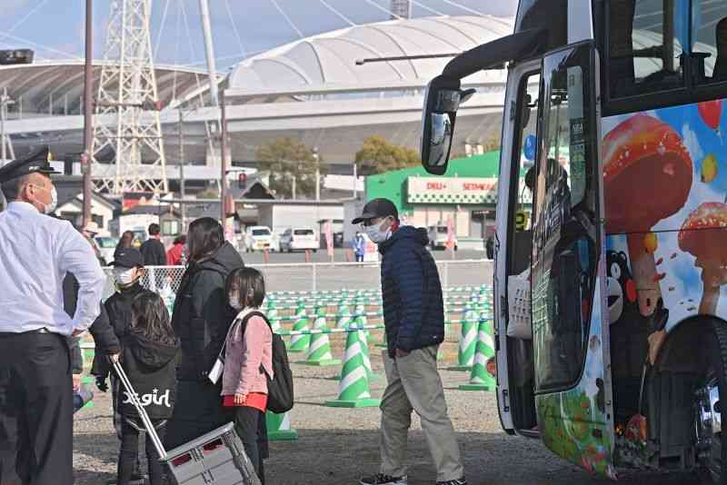 戸島ふれあい広場から乗車したシャトルバスを降り、えがお健康スタジアム（奥）へ向かう観客＝26日、熊本市東区（谷川剛）