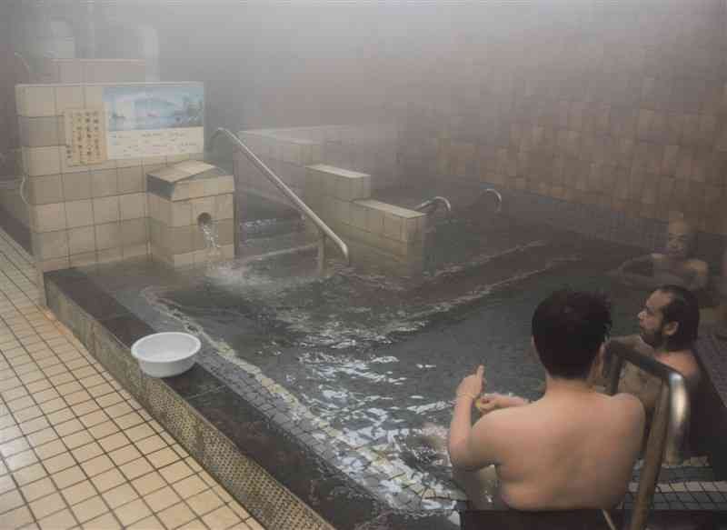 銭湯の湯船でリラックスする利用客＝熊本市中央区