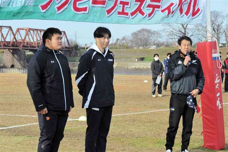 上杉太郎選手（帝京大、左）と上嶋友也選手（東福岡高、中央）をジュニア選手に紹介する玉名グリーンベルトラグビースクールの仲山延男監督（右）＝玉名市