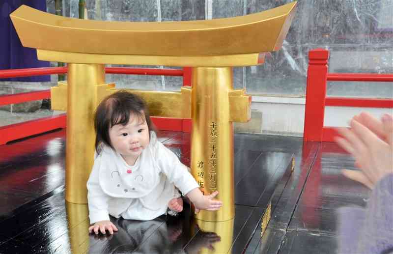 粟嶋神社のミニ鳥居をくぐる赤ちゃん＝宇土市