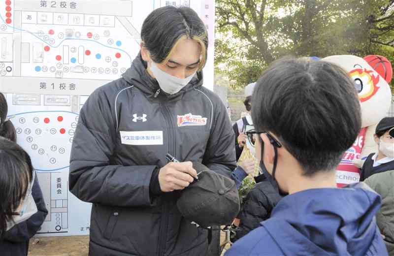 児童の帽子にサインする山本柊輔選手＝熊本市西区