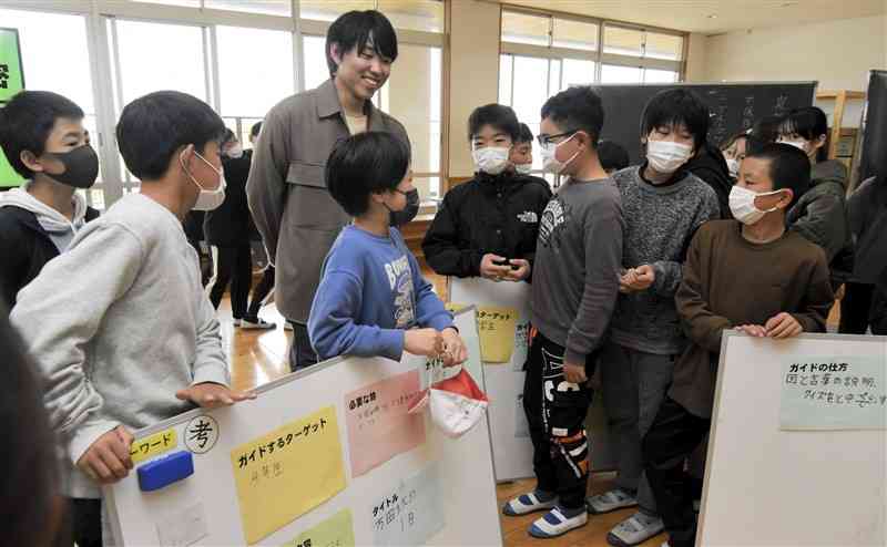 炭鉱電車を解説するアイデアを炭鉱電車保存会の磯野隼さん（中央奥）に発表する万田小の児童たち＝荒尾市