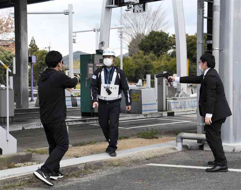 訓練で警察官がふんする強盗役に襲われる料金所の職員（中央）＝熊本市北区