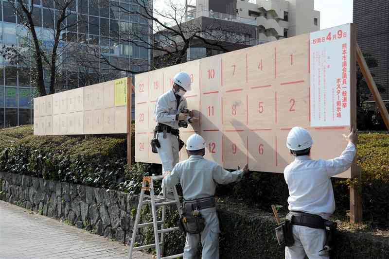 設置作業が始まった県議選（左）と熊本市議選のポスター掲示板＝10日、熊本市役所の市議会棟前