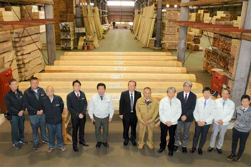 首里城正殿の向拝柱などに使用される木材と県内の関係者ら＝熊本市東区
