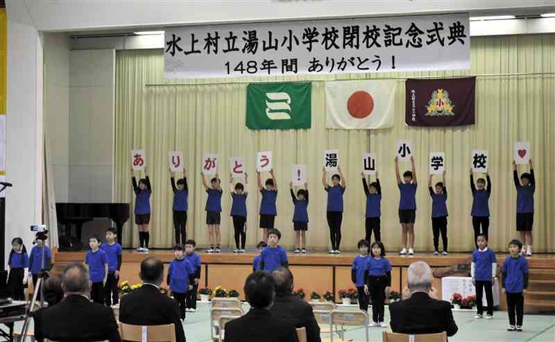 湯山小の閉校式でダンスを披露後に、「ありがとう！湯山小学校」のメッセージを掲げる児童＝水上村