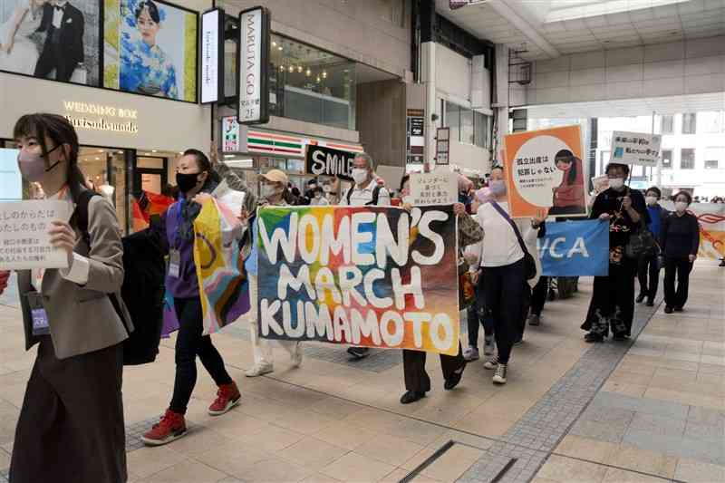 女性の権利やジェンダー平等を求めて練り歩く参加者ら＝熊本市中央区