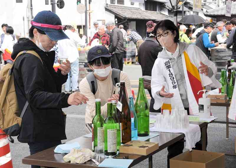 千代の園酒造の新酒イベント「春の蔵開き」で、飲み比べる酒を品定めする来場客＝山鹿市