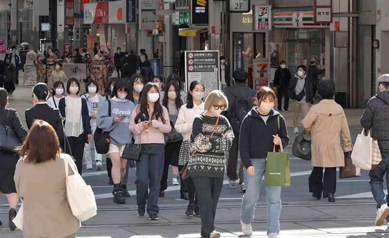 マスク着用が個人の判断に委ねられた13日、マスクをして繁華街を歩く人たち＝熊本市中央区の通町筋（谷川剛）