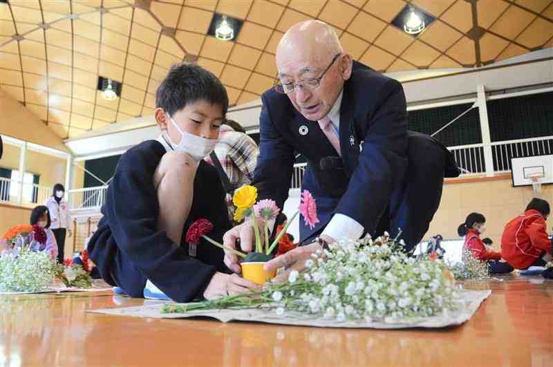 児童にフラワーアレンジメント作りを手ほどきする三角修さん＝菊池市