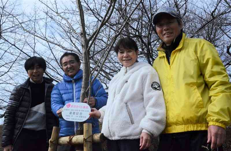 還暦記念のプレートを取り付けた渡邉和博さん（左から2人目）ら同級生4人＝菊池市